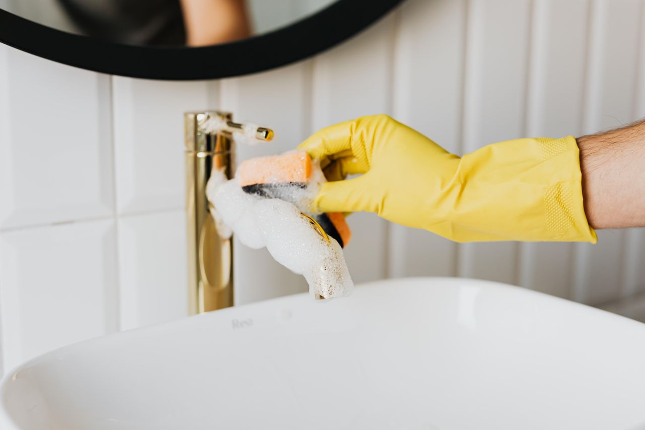 Person scrubbing bathtub faucet
